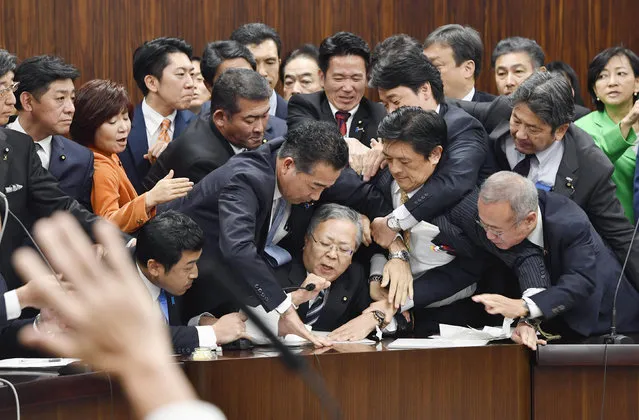 Japan's opposition parties' members try to stop Judicial Affairs Committee Chairman Shinichi Yokoyama, bottom center, from moving to hold a vote for a bill to revise an immigration control law, at upper house committee in Tokyo early Saturday, December 8, 2018. Japan is preparing to officially open the door to foreign workers to do unskilled jobs and possibly eventually become citizens. (Photo by Yoshitaka Sugawara/Kyodo News via AP Photo)