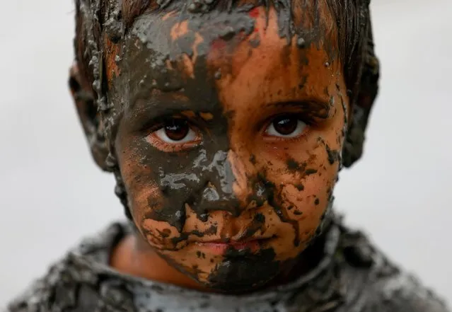A boy with mud covering his face looks on as he participates during National Paddy Day, also called Asar Pandra, that marks the commencement of rice crop planting in paddy fields as monsoon season arrives, in Bhaktapur, Nepal, June 29, 2021. (Photo by Navesh Chitrakar/Reuters)