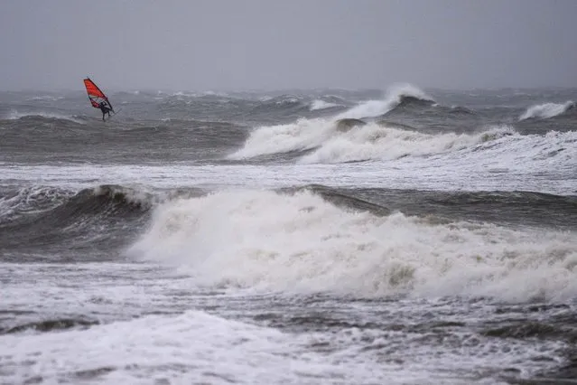 A wind surfer rides on waves at the Baltic Sea near Kuehlungsborn, Germany, Friday, October 20, 2023. Gale-force winds and floods struck several countries in Northern Europe as the region endured more heavy rain on Friday that forecasters say will continue into the weekend. (Photo by Matthias Schrader/AP Photo)