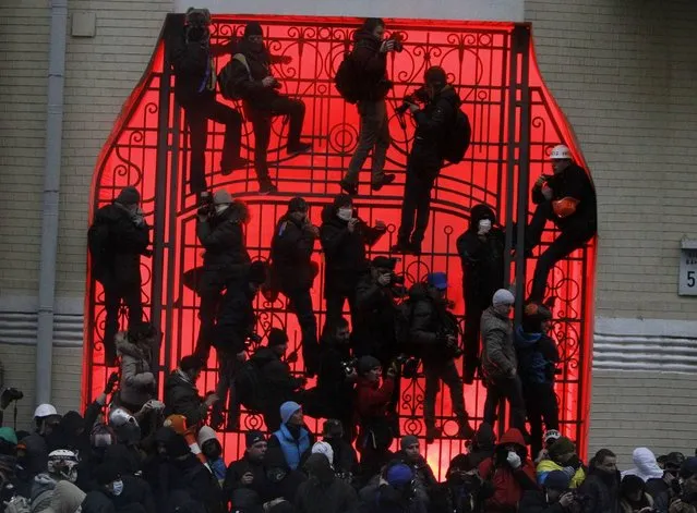 People climb up onto a gate near the presidential administration building during a rally held by supporters of EU integration in Kiev, December 1, 2013. (Photo by Gleb Garanich/Reuters)
