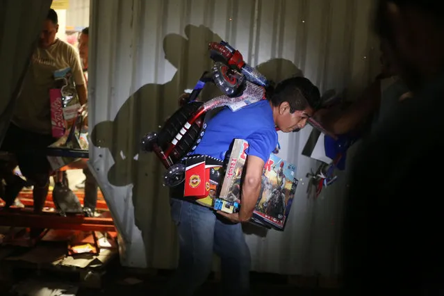 A man runs with toys that was looted from a store during a protest in the port of Veracruz, Mexico, on January 4, 2017, related to a 20 percent gasoline price increase. Looting broke out at dozens of stores in Mexico on the sidelines of protests against a steep gasoline price increase as authorities detained more than 200 people. (Photo by Ilse Huesca/AFP Photo)