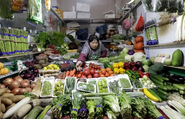 A vendor reaches out for vegetables at her shop in a market in Beijing, February 18, 2016. (Photo by Jason Lee/Reuters)