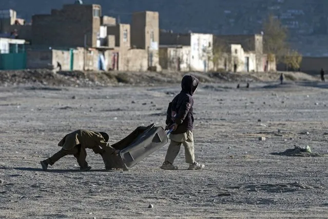 Afghan boys play with an abandoned bag near the Shuhada Lake in Kabul on December 4, 2023. (Photo by Wakil Kohsar/AFP Photo)