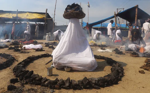 Sadhus or Hindu holy men offer prayers while sitting inside circles of burning “Upale” (or dried cow dung cakes) after taking a dip during the third “Shahi Snan” (grand bath) at “Kumbh Mela” or the Pitcher Festival, in Prayagraj, previously known as Allahabad, India, February 10, 2019. (Photo by Jitendra Prakash/Reuters)