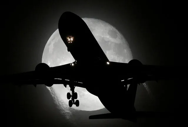 An aircraft passes in front of the moon as it makes its landing approach to Heathrow Airport in London, Britain on November 9, 2022. (Photo by Toby Melville/Reuters)