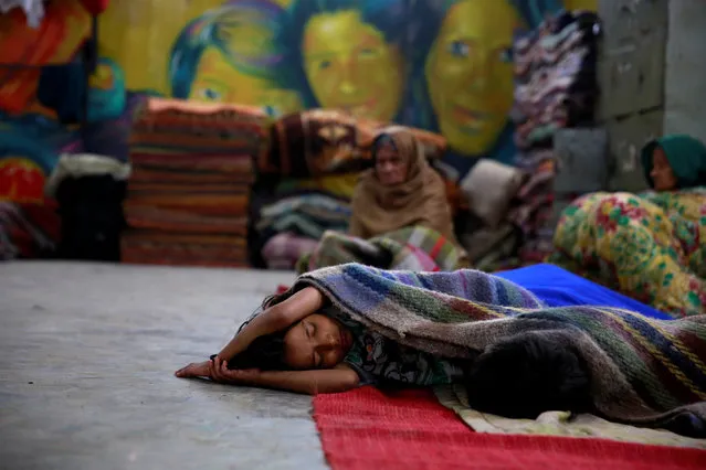 A child sleeps in a government shelter for homeless people to escape the cold in Delhi, India January 16, 2017. (Photo by Cathal McNaughton/Reuters)