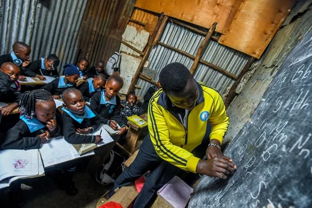 A teacher shows students how to write letters in a makeshift school as more than half of the people the country try to survive in shacks due to financial reasons such as inadequate schools, lack of infrastructure and insufficient school supplies in Kibera neighborhood of Nairobi, Kenya on January 10, 2024. (Photo by Gerald Anderson/Anadolu via Getty Images)