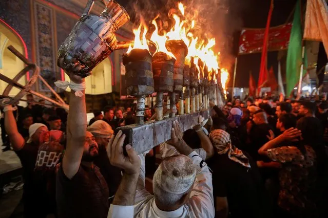Iraqi Shi'ite Muslims carry torches during a mourning ritual ahead of Ashura, the holiest day on the Shi'ite Muslim calendar, in the holy city of Najaf, Iraq, August 16, 2021. (Photo by Alaa Al-Marjani/Reuters)