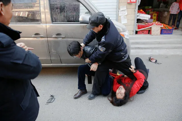 A member of a local public security force tries to overpower a man holding a hatchet as his wife screams at the Picun village, home to thousands of migrant workers in the suburbs of Beijing, China January 24, 2017. (Photo by Damir Sagolj/Reuters)