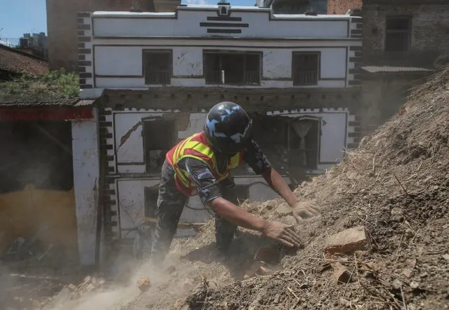 A member of Nepalese police personnel clears rubble with his hands while looking for survivors in the compound of a collapsed temple following Saturday's earthquake in Kathmandu, Nepal, April 27, 2015. (Photo by Danish Siddiqui/Reuters)