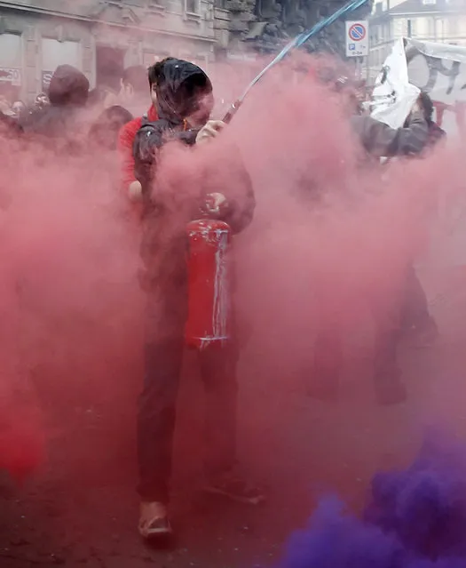 A man spatters paint on a shutter as he uses a fire extinguisher during a protest against Expo 2015 in Milan, Italy, Thursday, April 30, 2015. (Photo by Antonio Calanni/AP Photo)