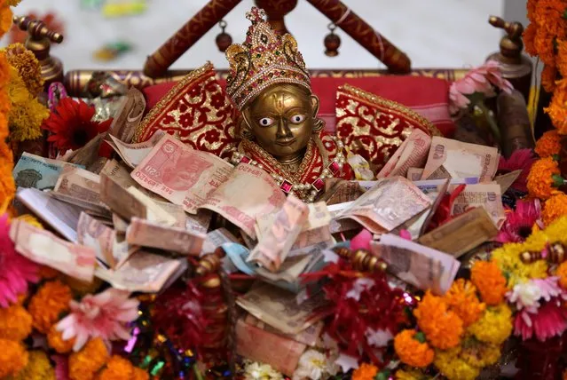Indian rupee notes are kept in front of an idol of Hindu Lord Rama as offerings by devotees, during Ramnavmi festival at a temple in Ahmedabad, India, April 14, 2019. (Photo by Amit Dave/Reuters)