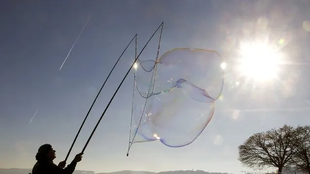 A man blows a giant soap bubble during sunny winter weather in Zurich February 10, 2015. (Photo by Arnd Wiegmann/Reuters)