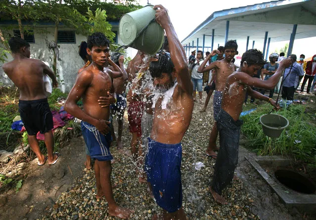 Ethnic Rohingya men take showers outside their temporary shelter in Langsa, Aceh province, Indonesia, Saturday, May 16, 2015. Boats filled with more than 2,000 desperate and hungry refugees from Myanmar and Bangladesh have arrived in Thailand, Malaysia and Indonesia in recent weeks, and thousands more migrants are believed to be adrift at sea after a crackdown on human traffickers prompted captains and smugglers to abandon their boats. (Photo by Binsar Bakkara/AP Photo)