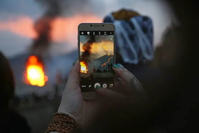 A woman uses her smart phone to take pictures of people light bonfires as they watch a torch procession up a hill during celebrations of the Kurdish New Year Newroz in Akre, Aqrah, Kurdistan Region, northern Iraq, 20 March 2017. Newroz, or Nowruz, which means “new day” in Persian language, marks the arrival of spring and the first day in the Iranian calendar. It is widely celebrated in the Persian and neighouring regions and recognized on the UNESCO List of the Intangible Cultural Heritage of Humanity. (Photo by Gailan Haji/EPA)