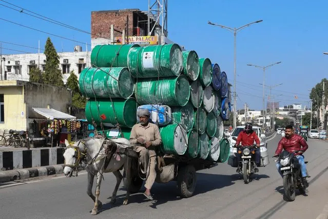 A man transports empty metal drums on a horse-drawn cart along a road in Amritsar on January 29, 2022. (Photo by Narinder Nanu/AFP Photo)