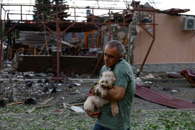 Local resident Vahe Ohandzanian, a 54-year-old, holds a dog next to his cafe heavily damaged by a Russian air strike, amid Russia's attack on Ukraine, in Kharkiv, Ukraine on May 22, 2024. (Photo by Valentyn Ogirenko/Reuters)