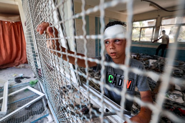 An injured boy stands by a window lattice in a destroyed classroom where people were sheltering at a school run by the UN Relief and Works Agency for Palestine Refugees (UNRWA) that was previously hit by Israeli bombardment, in the Nuseirat camp in the central Gaza Strip on June 7, 2024 amid the ongoing conflict in the Palestinian territory between Israel and Hamas. (Photo by Eyad Baba/AFP Photo)