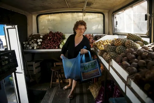 A woman looks for fruits to buy inside a bus called Sacolao in Santa Teresa neighborhood in Rio de Janeiro, Brazil, July 7, 2015. The bus, which began operating as a municipal initiative but has been taken over by a private enterprise, arrives every week in some neighborhoods to facilitate families with their grocery shopping and sells food at an affordable price, according to sellers. (Photo by Pilar Olivares/Reuters)