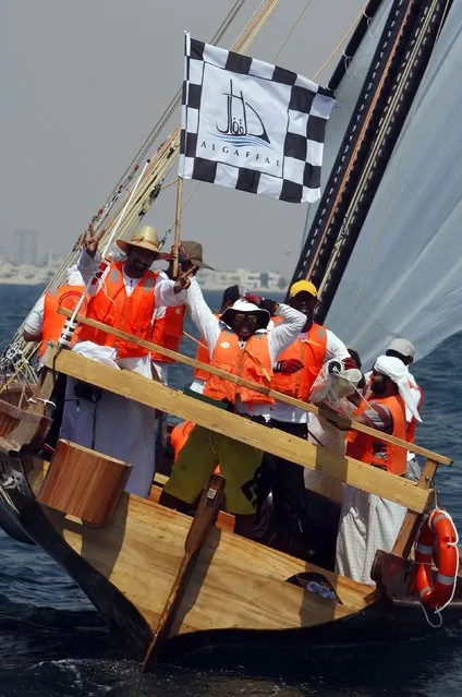 Navigator Ali Salem bin Kenaid al-Falasi (L) flashes a victory sign while his crewmate Rashed al-Humairi waves a flag to celebrate the team's victory in the Al Gaffal race, a long-distance traditional wooden boat or dhow sailing race, near Dubai May 18, 2014. (Photo by Martin Dokoupil/Reuters)