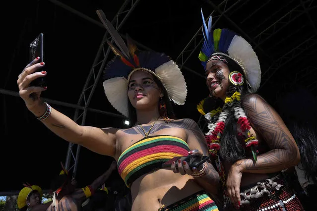 Xavante Indigenous women take selfies on opening day of the 18th edition of the annual Free Land Indigenous Camp in Brasilia, Brazil, Monday, April 4, 2022. The 10-day event aims to show the union of Brazil's Indigenous peoples in their fight for the demarcation of their lands and their rights. (Photo by Eraldo Peres/AP Photo)