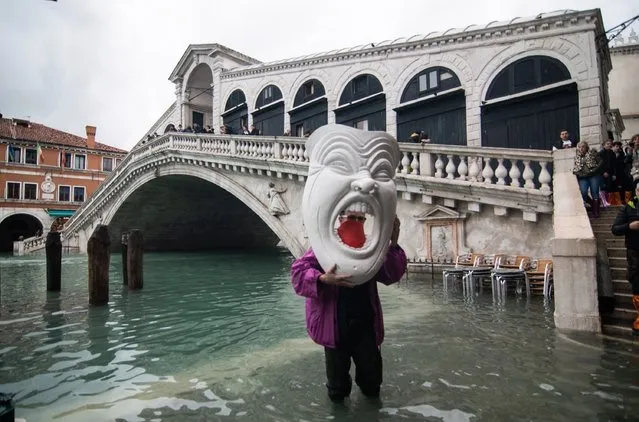A man with a giant mask stands close to Rialto bridge during an exceptionally high tide on November 17, 2019 in Venice, Italy. Another exceptionally high tide of 154 cm hits Venice today. (Photo by Awakening/Getty Images)