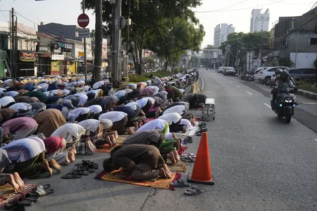 Muslim men perform Eid al-Fitr prayer marking the end of the holy fasting month of Ramadan, on a street outside an overflowed mosque in Jakarta, Indonesia, Monday, May 2, 2022. (Photo by Dita Alangkara/AP Photo)