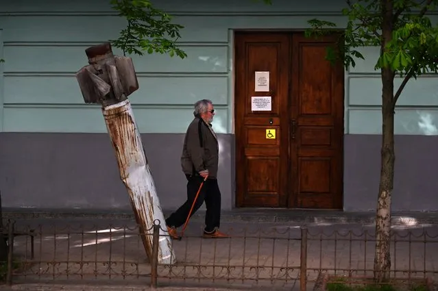 A pedestrian walks past a Russian rocket outside the National Museum of Military History of Ukraine in Kyiv, on May 5, 2022. The exhibit's curator Pavlo Netesov hopes the freshly destroyed equipment will serve as a visible reminder of the war's toll to residents in downtown Kyiv – who have been largely spared from the harsh ground fighting that has erupted elsewhere across the country. (Photo by Sergei Supinsky/AFP Photo)