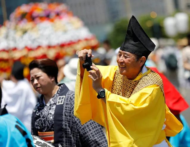 A participant dressed in an ancient Japanese costume takes photos as he takes part in a parade at the Imperial Palace during the Sanno Festival in Tokyo, Japan June 10, 2016. (Photo by Toru Hanai/Reuters)