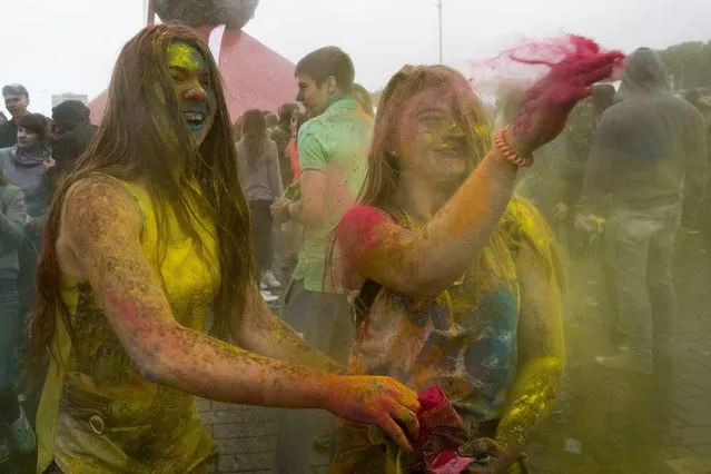 Girls throw powdered paint during the Festival of Colours in Moscow, Russia, Sunday, June 12, 2016. (Photo by Alexander Zemlianichenko/AP Photo)