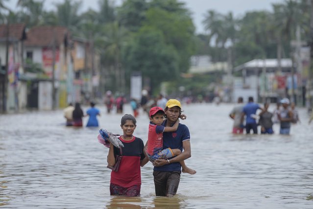 People wade through a flooded street in Biyagama, a suburb of Colombo, Sri Lanka, Monday, June 3, 2023. (Photo by Eranga Jayawardena/AP Photo)