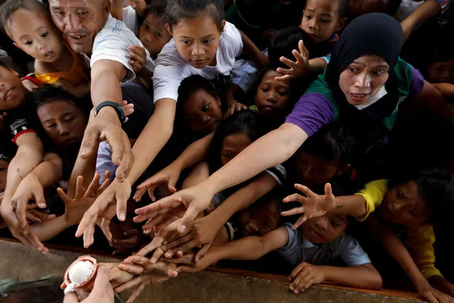 People reach to get ice cream at an evacuation center outside the city as army troops continue their assault against insurgents from the Maute group in Marawi city, Philippines, July 5, 2017. (Photo by Jorge Silva/Reuters)