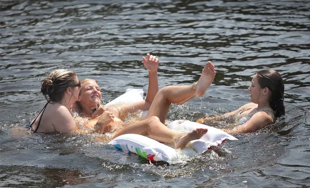 Michelle Wainright, left, and Logan Register, right, try to dump Kelsi Wainright from a float while enjoying breeze and water of the Neuse River at Green Springs in James City, N.C., Thursday afternoon, June 19, 2014, (Photo by Chuck Beckley/AP Photo/The Sun Journal)