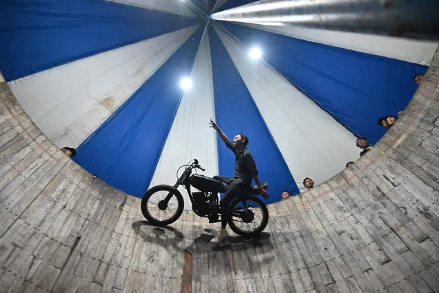 This photo taken on April 30, 2022 shows a rider of the “wall of death”, locally known as a tong stand, performing inside a six-metre high wall at a night carnival in Bogor. (Photo by Adek Berry/AFP Photo)