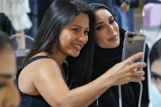 Lori Ann Grejarte of Cavite, Philippines, left, takes a selfie with her mobile phone with Emirati artist Rowdha Alsayegh, right, at an event featuring makeup artist Mario Dedivanovic at City Center Mirdif Mall in Dubai, United Arab Emirates, Friday, October 29, 2021. The coronavirus pandemic has been difficult for the makeup industry, with the surge in home working and cancellations of many social events like weddings. Sales in the multi-billion-dollar Mideast makeup market are beginning to improve as vaccinations see the pandemic wane. (Photo by Jon Gambrell/AP Photo)