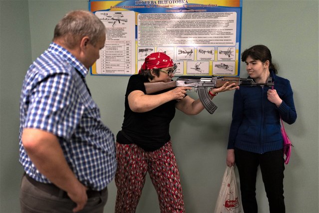 Iada Bondarenko, center with a mock AK-47 rifle, and Viktoria Ludchak, left, participate in firearms training for civilians amid the country's ongoing war against Russia in Kyiv, Ukraine, Tuesday, July 11, 2023. (Photo by Jae C. Hong/AP Photo)