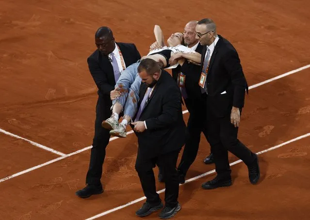 A protester is carried off the court after tying themselves to the net during the Men's Singles Semi Final match between Marin Cilic of Croatia and Casper Ruud of Norway on Day 13 of The 2022 French Open at Roland Garros on June 03, 2022 in Paris, France. (Photo by Yves Herman/Reuters)