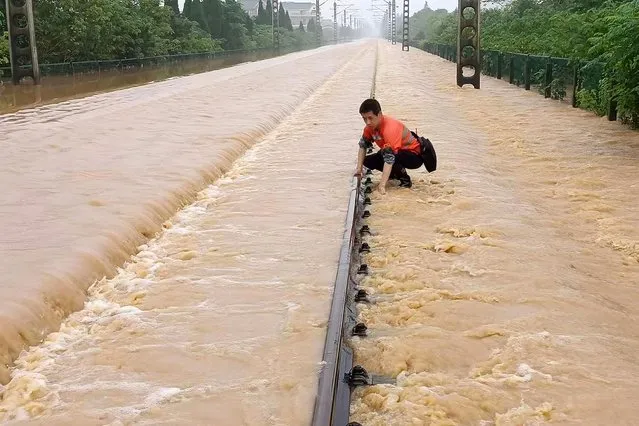 A worker checks a section of flooded railway in Shangrao in central China's Jiangxi province, Tuesday, June 21, 2022. Major flooding has forced the evacuation of tens of thousands of people in southern China, with more rain expected. (Photo by Chinatopix via AP Photo)