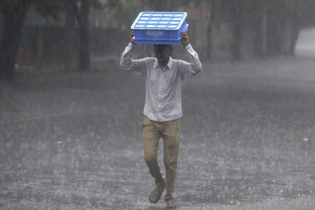 A man uses a plastic crate to cover himself during heavy rains in Chandigarh, India, June 28, 2016. (Photo by Ajay Verma/Reuters)
