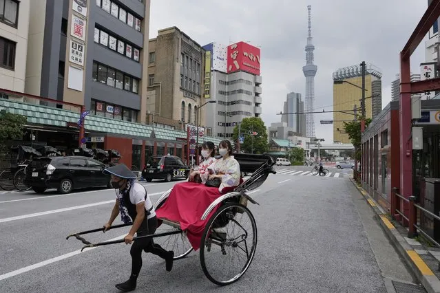 A rickshaw puller carries his customers around Tokyo's Asakusa area famous for sightseeing, Wednesday, June 22, 2022. (Photo by Hiro Komae/AP Photo)