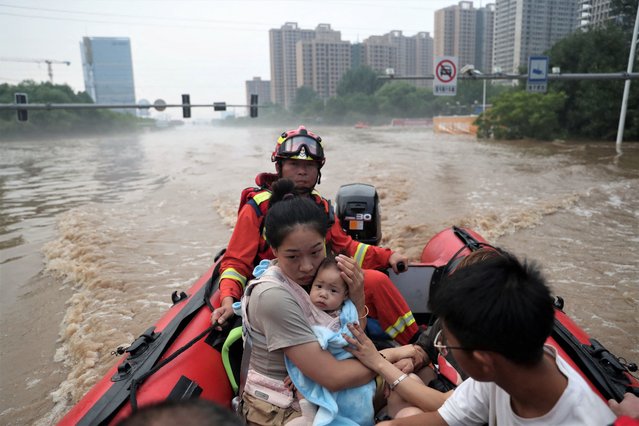 A woman holds a baby as rescue workers evacuate residents stranded by floodwaters after heavy rainfall in the city Zhuozhou, China on August 3, 2023. More than 134,000 Zhuozhou residents have been affected by the flooding, which has washed away cars and buses, destroyed bridges and knocked out power supplies as the torrential rain turned roads into rivers across the region. (Photo by China Daily via Reuters)