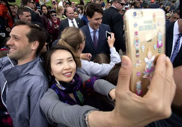 A woman takes a selfie of herself with Canada Prime Minister Justin Trudeau in the background on Parliament Hill following a group photo of parliamentarians to mark the 150th anniversary of parliament, Wednesday, June 8, 2016 in Ottawa. (Photo by Adrian Wyld/The Canadian Press via AP Photo)