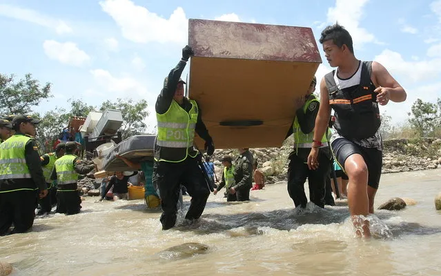 Colombian police help fellow citizens carry their belongings across the Tachira River into Colombia's community of La Parada, across the border with San Antonio del Tachira, Venezuela, Tuesday, August 25, 2015. (Photo by Efrain Patino/AP Photo)