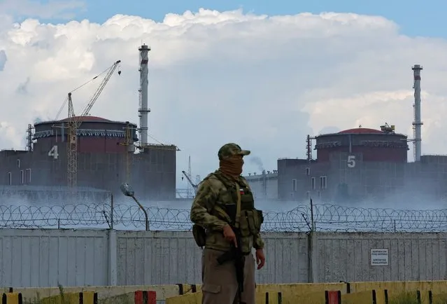 A serviceman with a Russian flag on his uniform stands guard near the Zaporizhzhia Nuclear Power Plant in the course of Ukraine-Russia conflict outside the Russian-controlled city of Enerhodar in the Zaporizhzhia region, Ukraine on August 4, 2022. (Photo by Alexander Ermochenko/Reuters)