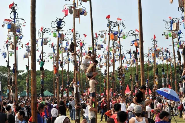 Indonesians participate in a local competition called “panjat pinang” in which people try to climb greased poles that have prizes and flags attached to the top, during an event to celebrate Indonesia's Independence Day in Jakarta on August 17, 2014. (Photo by Adek Berry/AFP Photo)