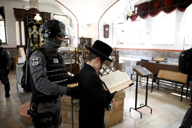 An Israeli policeman removes an ultra-Orthodox Jewish youth from a synagogue before it is closed by police as they enforce restrictions of a partial lockdown against the coronavirus disease (COVID-19) in Mea Shearim neighbourhood of Jerusalem on March 30, 2020. (Photo by Ronen Zvulun/Reuters)