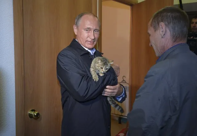 Russian President Vladimir Putin holds a cat while inspecting reconstruction of houses for people who suffered from wildfires in the village of Krasnopolye at the Siberian Khakasiya region, Russia, September 4, 2015. (Photo by Alexei Druzhinin/Reuters/RIA Novosti/Kremlin)