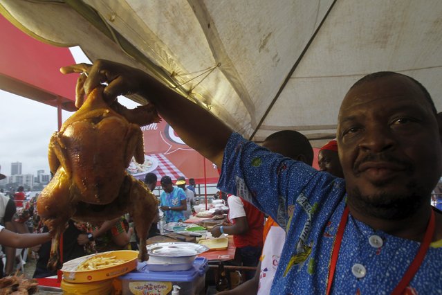 A cook shows a grilled chicken to visitors during the Festival des Grillades, in the yard of the Culture Palace of Abidjan, September 6, 2015. (Photo by Luc Gnago/Reuters)