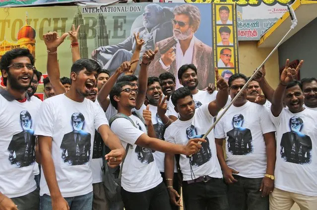 Fans of Indian superstar Rajinikanth take a selfie outside a cinema hall to celebrate the screening of “Kabali” in Chennai, India, Friday, July 22, 2016. Private companies declared a holiday and parents kept children out of school as an air of celebration swept southern India for the premiere of Rajinikanth’s latest film. Hundreds of thousands of Rajinikanth fans thronged cinemas across Tamil-language India and Malaysia to catch the pre-dawn showing of “Kabali”, a gangster movie that left patrons jumping from their seats and dancing in the aisles at the sight of their hero. (Photo by Aijaz Rahi/AP Photo)