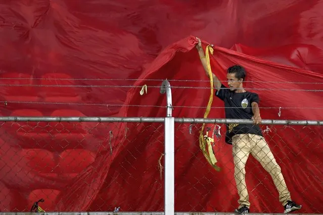 A soccer fan pulls on a giant red flag as he. stands on a fence during a Copa Sudamericana first leg quarter-final soccer match between Venezuela's Deportivo Tachira and Ecuador's Independiente del Valle in San Cristobal, Venezuela, Tuesday, August 2, 2022. (Photo by Matias Delacroix/AP Photo)